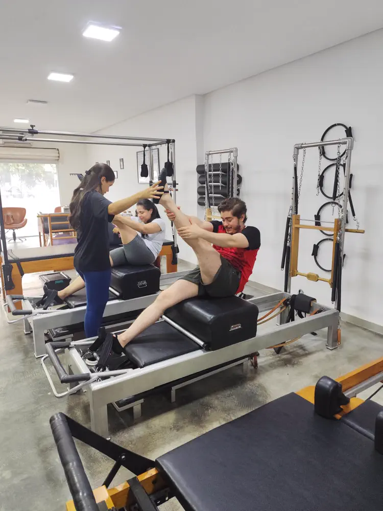 Professora ajustando o exercício de uma aluna no Reformer durante aula de Pilates terapêutico no Espaço Vitafit, em Vila Brasília, Aparecida de Goiânia