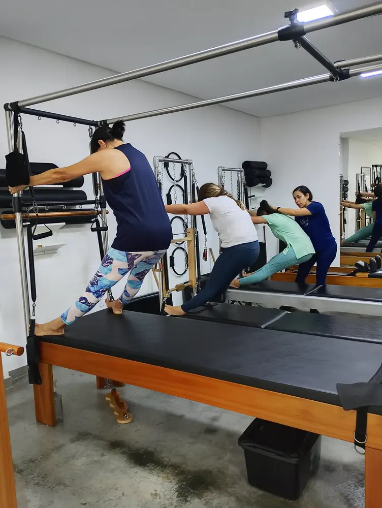 Professora corrigindo a postura de alunos durante aula de Pilates no Espaço Vitafit Pilates, em Vila Brasília, Aparecida de Goiânia